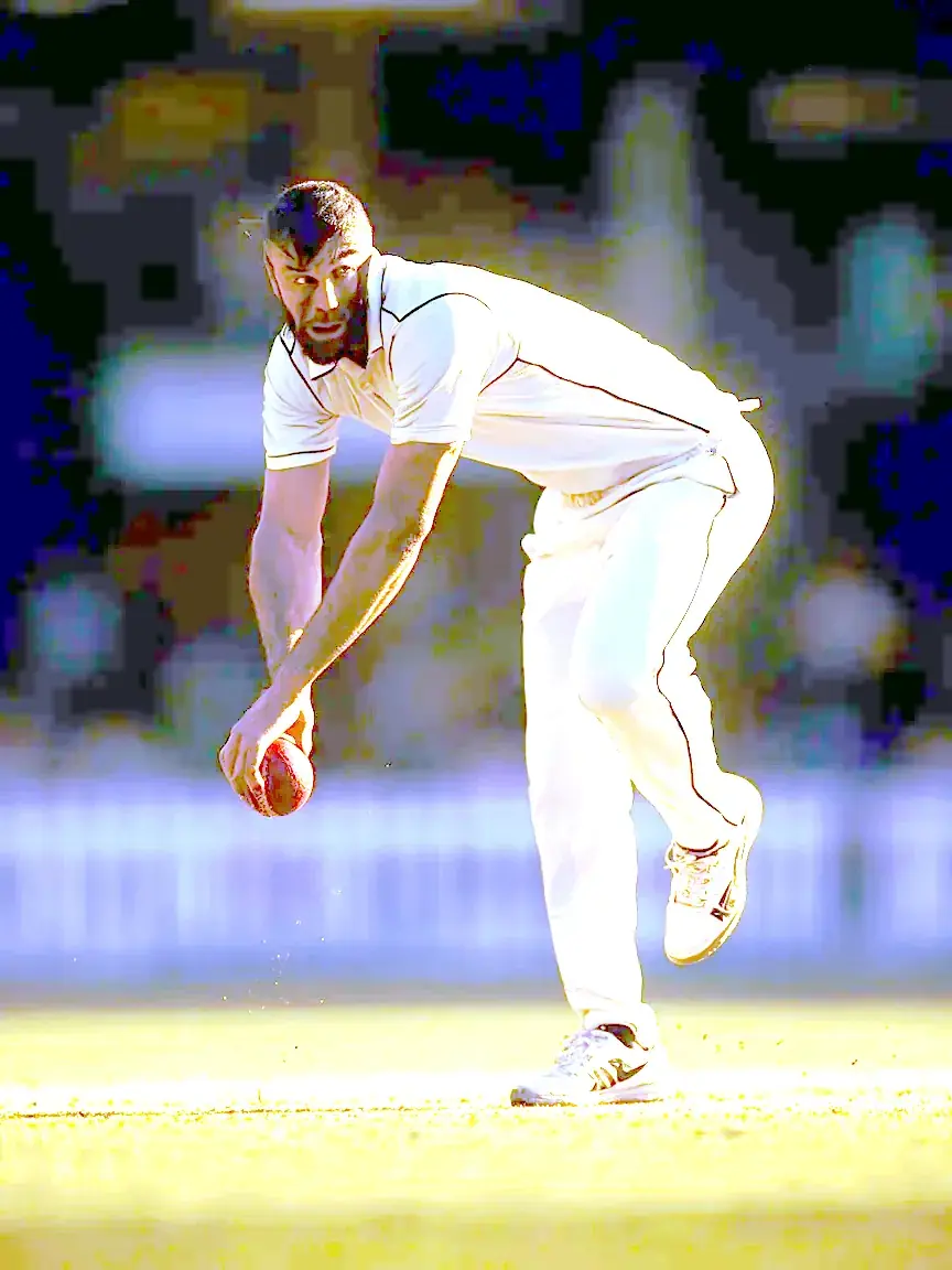A bowler delivers the ball at pace during a floodlit session
