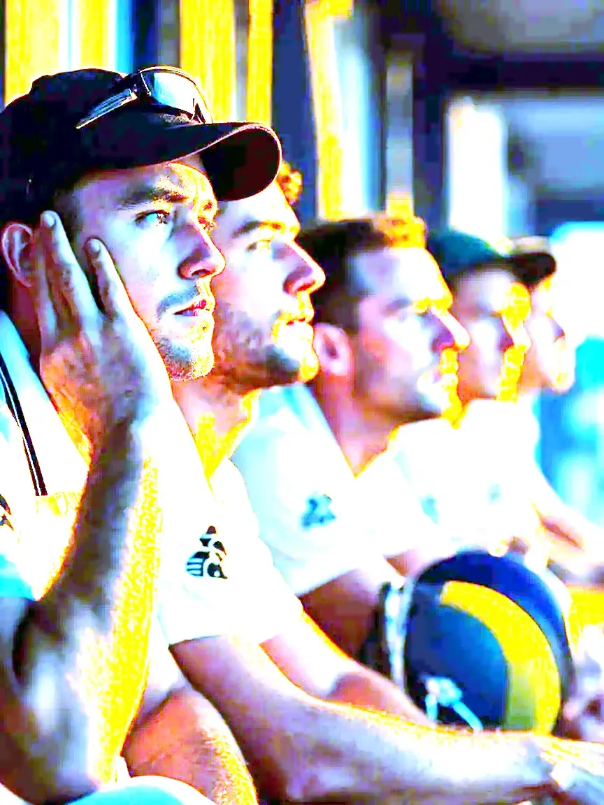 Reserve players watch attentively from the dugout during a night match